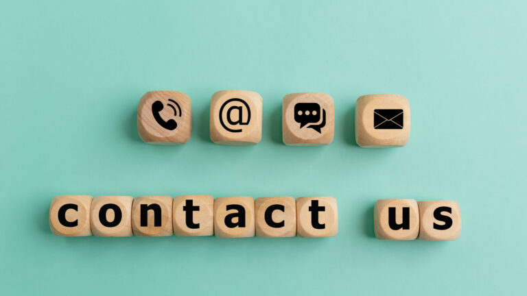 Wooden blocks showing phone, email, chat, and letter icons above blocks spelling “contact us” on a light blue background, highlighting the usability of your Contact page for an improved customer experience.