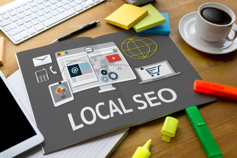 An open notebook with “LOCAL SEO” and digital marketing icons, surrounded by highlighters, sticky notes, a keyboard, coffee cup, and smartphone on a desk—perfect for local businesses looking to boost their website content strategies this summer.